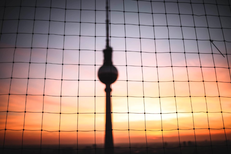 silhouette photo of hanging decor behind chain link fence at golden hour