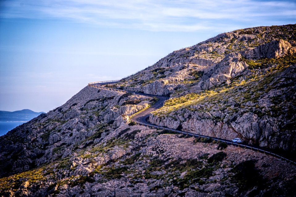 white car traveling on road near mountain