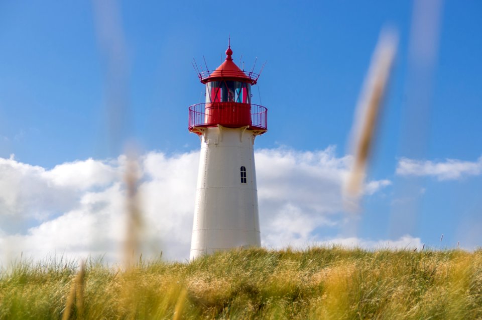white and red lighthouse under blue and white cloudy sky photo