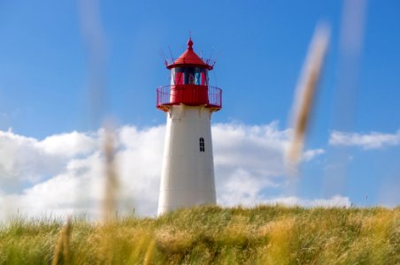 white and red lighthouse under blue and white cloudy sky photo photo