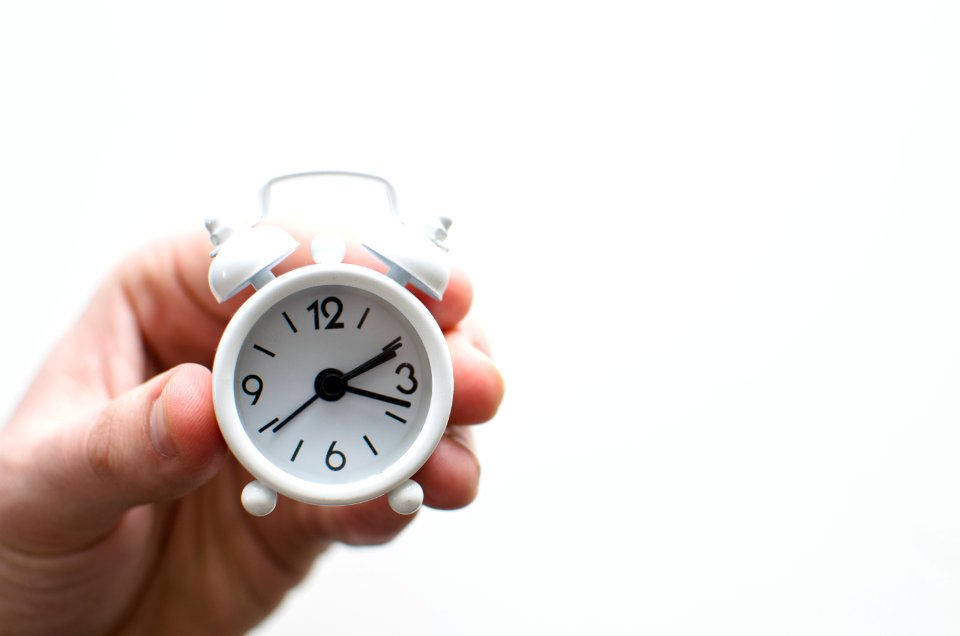 person holding white mini bell alarmclock