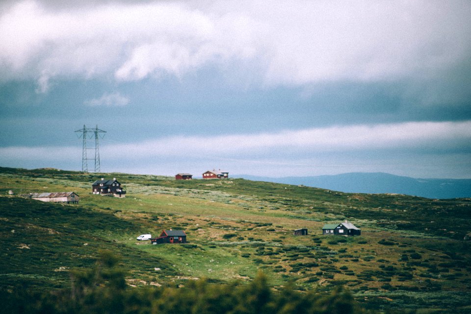 four houses on green grass field under cloudy sky