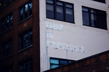 white Time Is Precious signage building at daytime photo