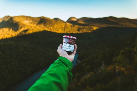 person holding clear glass jar with cap near mountain photo
