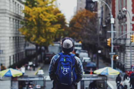 man with backpack on street in shallow focus photography photo