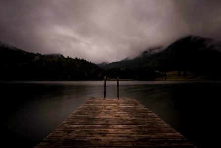 brown wooden dock near lake under cloudy sky