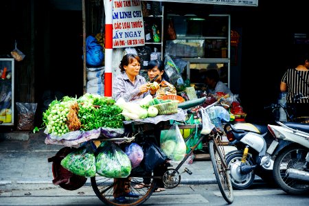 woman slicing vegetable on her bike stand near store photo