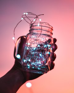 person holding clear glass mason jar with strip lights inside photo