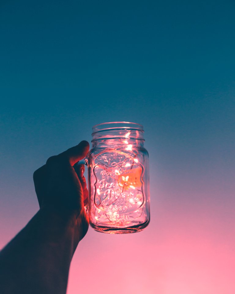 person holding clear glass mug jar