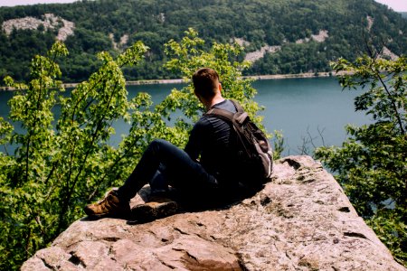 person with backpack sitting on gray rock photo