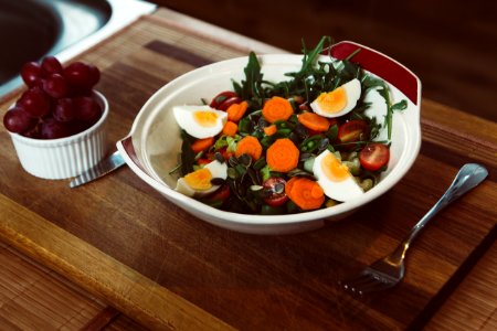 bowl of salad with slide of cooked egg with grapes on the side photo