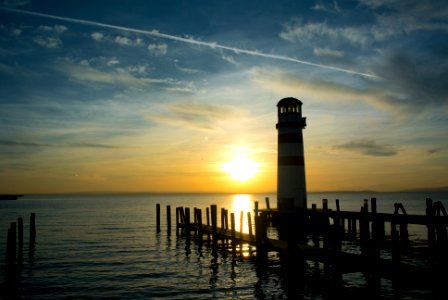 silhouette of lighthouse on sea during sunset