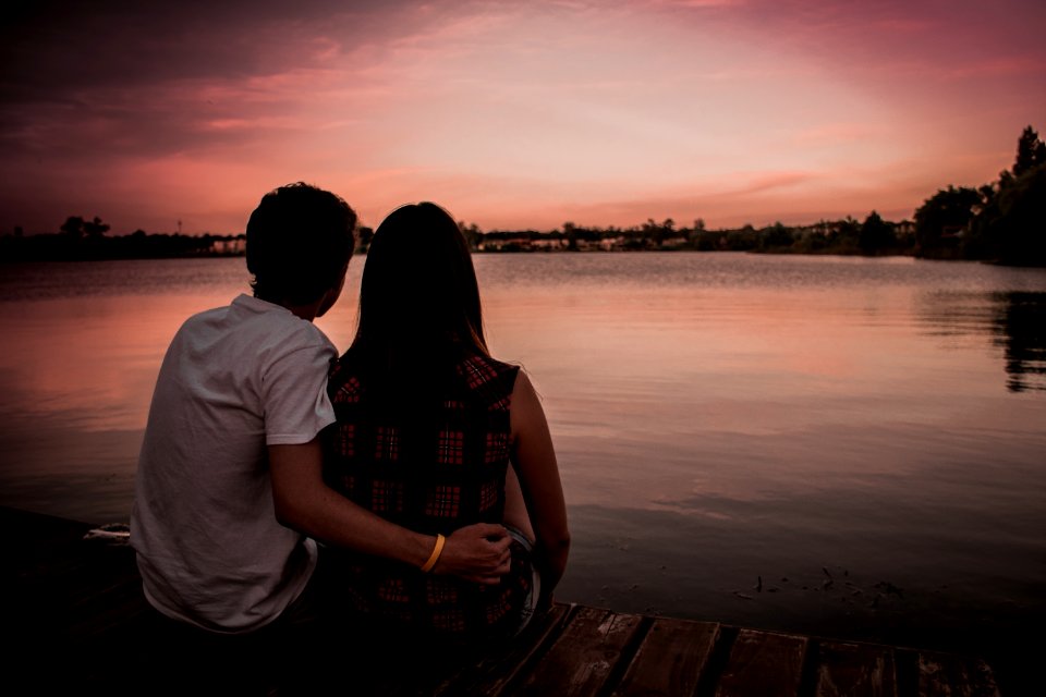 man and woman sitting on dock