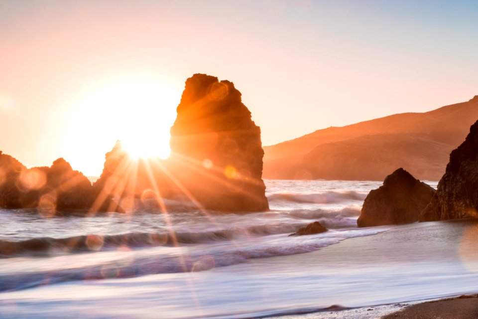 golden hour photography of rock formation on body of water