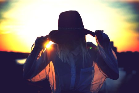 silhouette of woman holding her hat