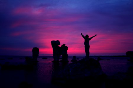 person standing on rock formation with arms in air photo