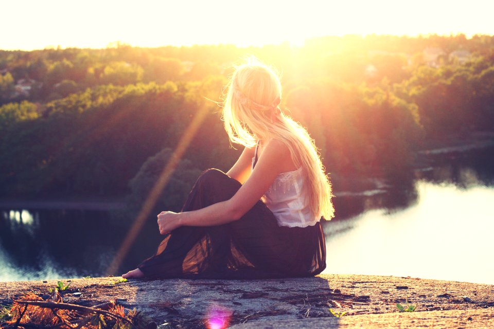 woman sitting on brown surface watching at body of water