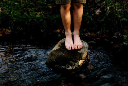 person standing on stone at center of body of water photo