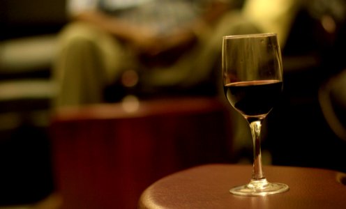 shallow focus photography of wine in wineglass on brown wooden table photo