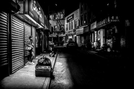 grayscale photography of woman standing infront of store shutter door at night photo