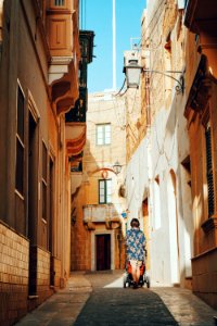 woman pushing stroller passing through alleyt