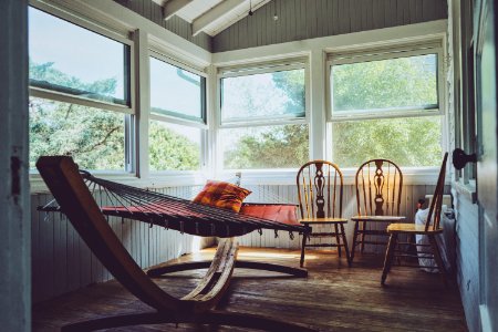 photography of grey, white, and brown wooden house interior with three brown wooden Windsor chairs beside brown hammock with glass windows photo