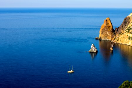 aerial photography of white ship on sea near rock formations under blue sky during daytime photo