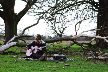 men holding a guitar near trees during daytime photo