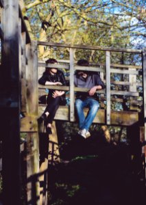 man and woman sitting on side of wooden bridge photo