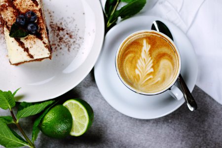 flat lay photography of coffee in teacup near plate of sliced cake photo