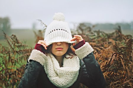 woman in white black sweater holding white knit cap photo