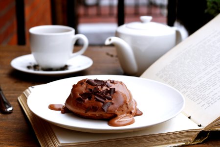 Chocolate dessert on an open book with a tea pot and tea cup in the background photo
