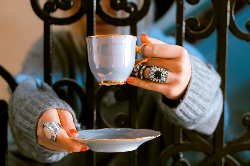 person holding teacup and saucer