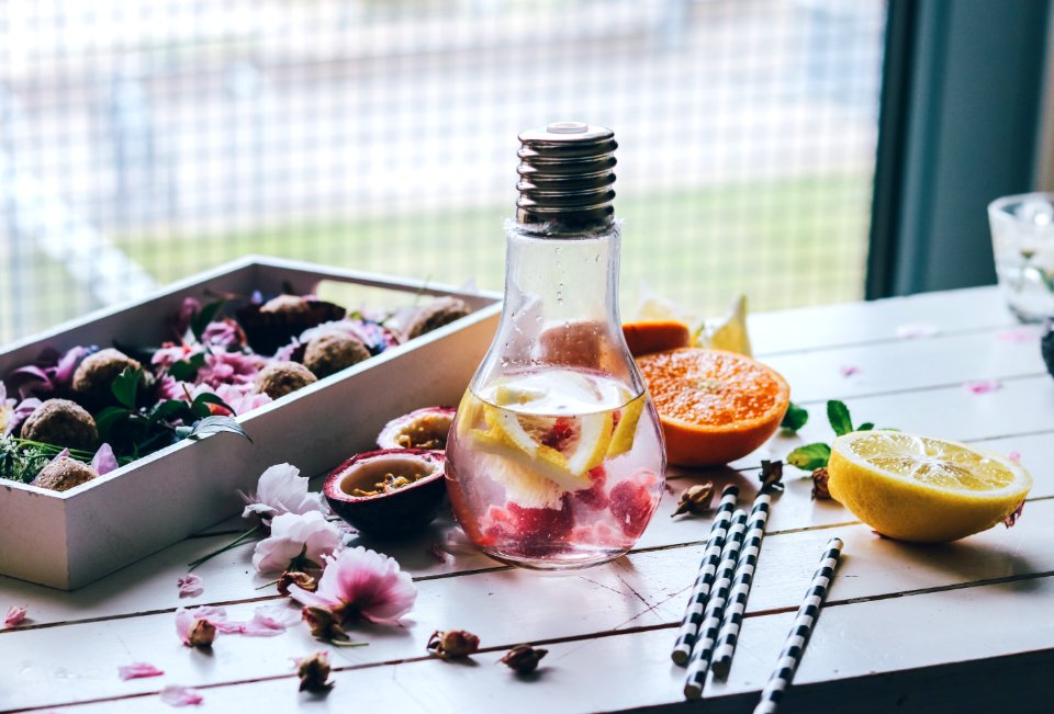 clear glass light bulb pitcher with sliced lemon and orange fruits on top of white table photo