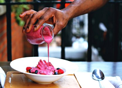 person pouring pink liquid on fruits