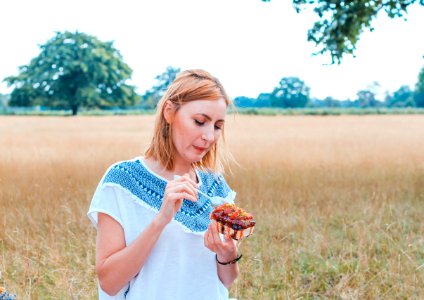 shallow focus photo of woman in white and blue T-shirt eating dessert