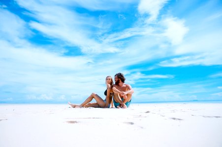 man sitting beside of woman in black bikini top