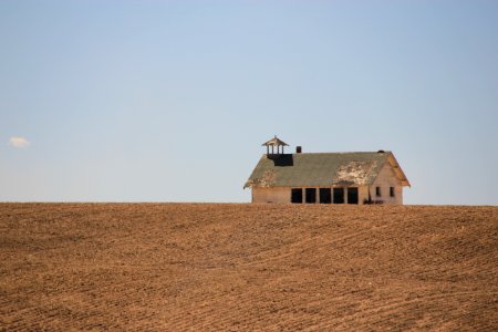 brown and white house on brown field under gray sky photo