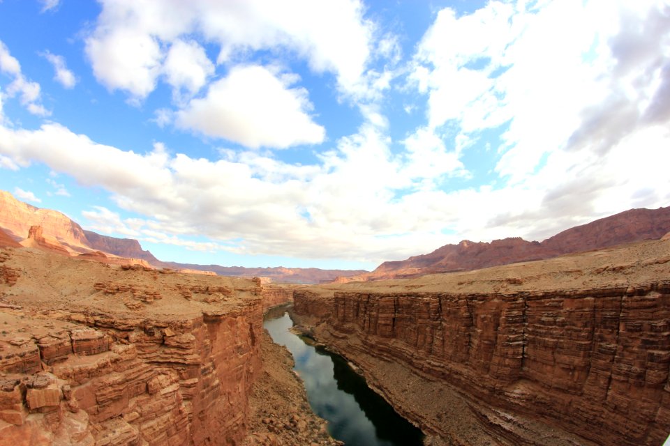 brown rocky mountain beside river under blue sky during daytime