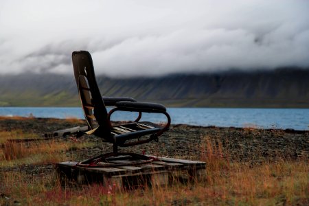 black metal chair on brown grass near body of water during daytime photo