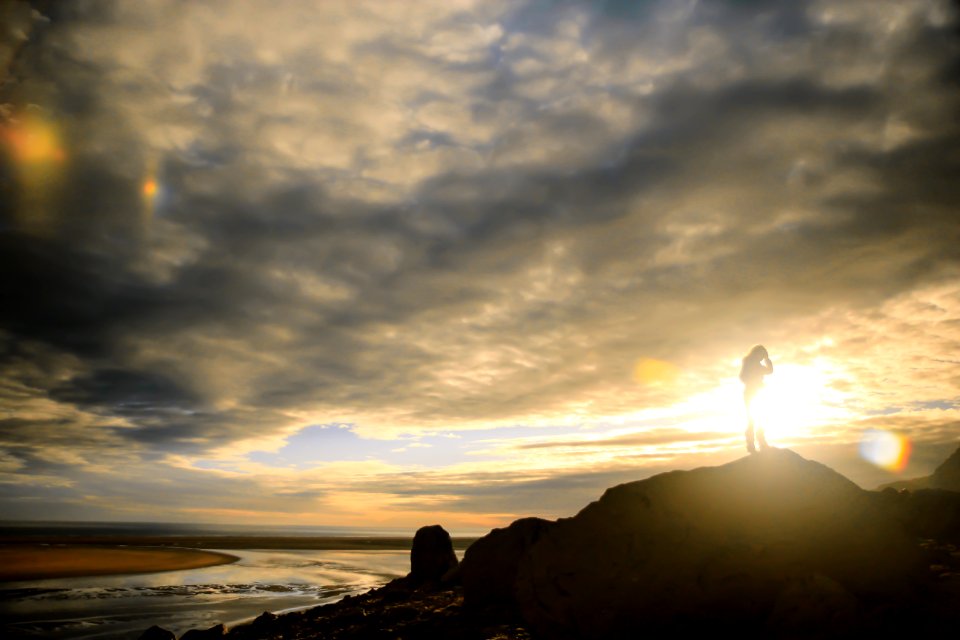 person standing on rock formation near body of water during daytime