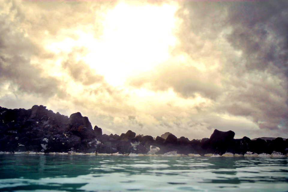 rocky mountain beside body of water under cloudy sky during daytime photo