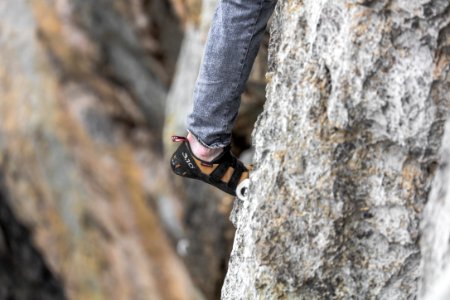 person in blue denim jeans and black hiking shoes standing on gray rock during daytime photo
