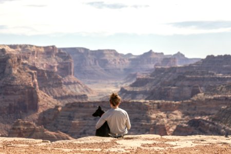 person with dog sitting on Grand Canyon cliff photo