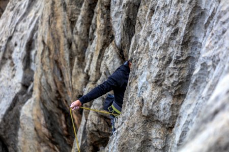 man in black jacket climbing on gray rock mountain during daytime photo