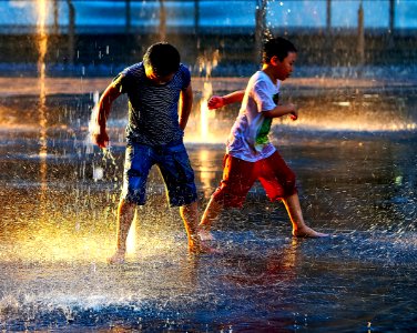 two boy standing in the rain during daytime