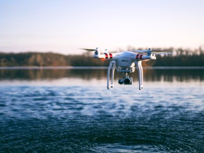 white quadcopter drone flying above body of water photo
