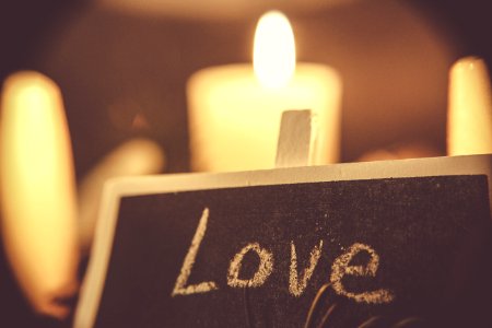 A black chalkboard that says "Love," with white candles in the background. photo