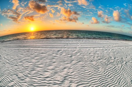 gray sand near body of water under white and blue sky at sunrise photo