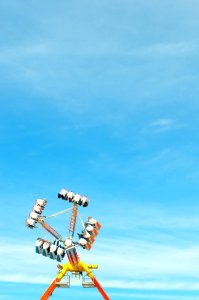 photo of yellow, orange, and blue amusement park ride under clear blue sky